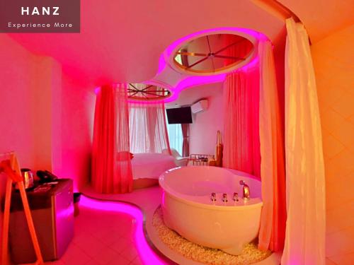 胡志明市的住宿－HANZ MeGusta Hotel Ben Thanh，粉红色的浴室设有浴缸和床。