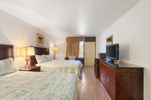 a hotel room with two beds and a flat screen tv at Williamsburg Suites in Williamsburg