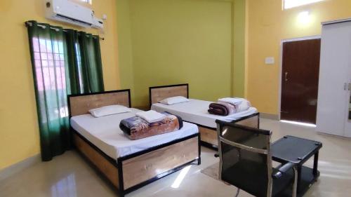 two beds in a room with a chair at Hengdang Resort in Hārmutigāon