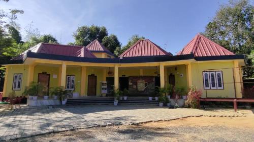 una casa amarilla con techo rojo en Hengdang Resort, en Hārmutigāon