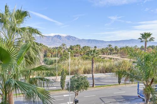 an empty street with palm trees and mountains in the background at Apartamento Playa Granada Golf in Motril