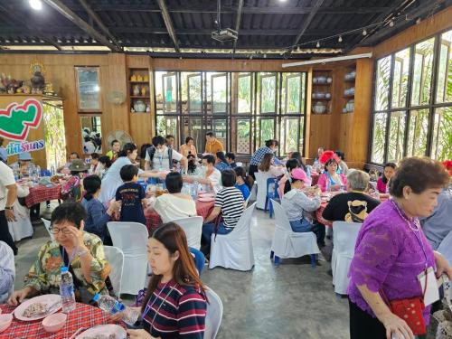 un grupo de personas sentadas en mesas en un restaurante en Baan Rai Somkiat Homestay Saraburi, en Ban Lam Thong Lang
