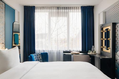 a hotel room with a bed and a desk and a window at Eden Hotel Amsterdam in Amsterdam