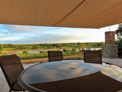 a glass table with chairs and a view of a river at The South Post @ Kruger in Marloth Park