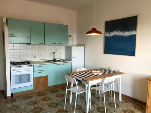 cocina con armarios azules, mesa y sillas en Be Your Home - Casa Raffaello, en Santa Marinella