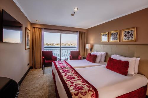 een hotelkamer met 2 bedden en een groot raam bij Steigenberger Legacy Nile Cruise - Every Monday 07 & 04 Nights from Luxor - Every Friday 03 Nights from Aswan in Luxor
