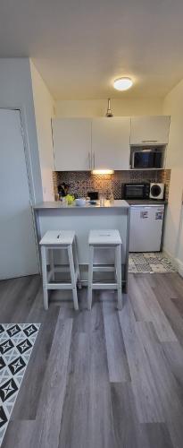 - une cuisine avec un comptoir et deux tabourets dans l'établissement LOGEMENT CLICHY, à Clichy