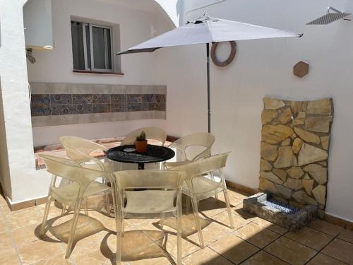 ein Esszimmer mit einem Tisch, Stühlen und einem Sonnenschirm in der Unterkunft Alojamiento Rural Los Corrales in Algodonales