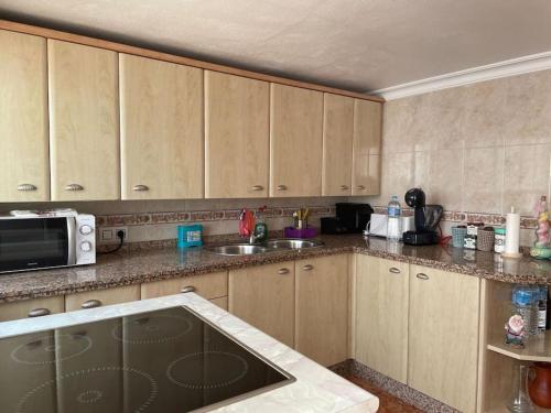 une cuisine avec des armoires en bois et un micro-ondes dans l'établissement Alojamiento Rural Los Corrales, à Algodonales