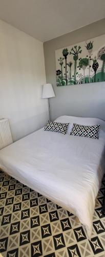 une chambre avec un grand lit blanc avec une lampe dans l'établissement LOGEMENT CLICHY, à Clichy