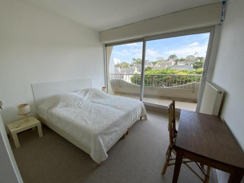 une chambre avec un lit et une grande fenêtre dans l'établissement 451 - Appartement à ERQUY, en bordure de la très belle plage de CAROUAL, à Erquy