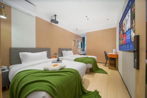 a hotel room with three beds with green blankets at Guangzhou Yashe Hotel - Keyun Road Metro Station Pazhou Convention and Exhibition Store in Guangzhou
