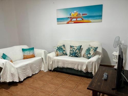 uma sala de estar com duas cadeiras e um quadro na parede em Habitación matrimonial en un bajo baño compartido Areas compartidas em Abades