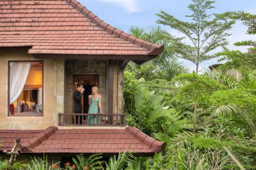 a couple standing on a balcony of a house at Sakti Garden Resort & Spa in Ubud