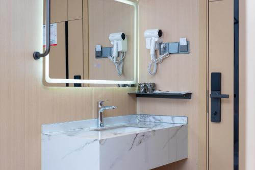 a bathroom with a sink and a mirror at Guangzhou Yashe Hotel - Keyun Road Metro Station Pazhou Convention and Exhibition Store in Guangzhou