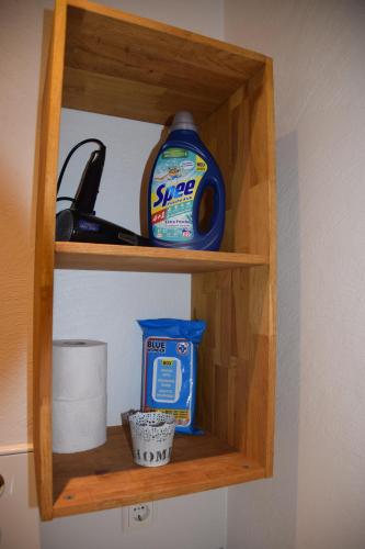 a wooden shelf with a bottle of sunscreen and a container of toilet paper at Ferienwohnung am Rathaus in Landstuhl
