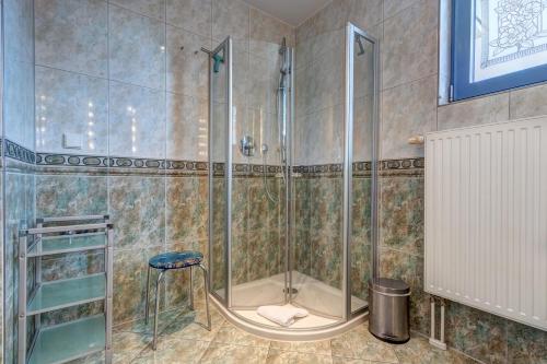 ein Bad mit einer Dusche mit einem Hocker in der Unterkunft Villa Seeschloss in Heringsdorf