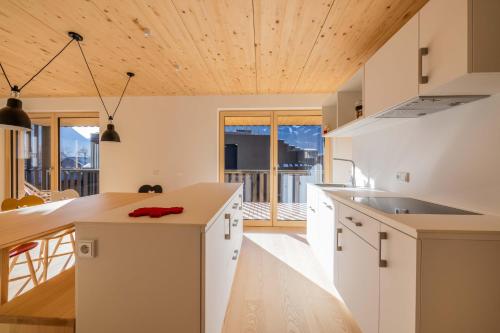 a kitchen with white cabinets and a wooden ceiling at Apartmenthaus A24 in Schruns-Tschagguns