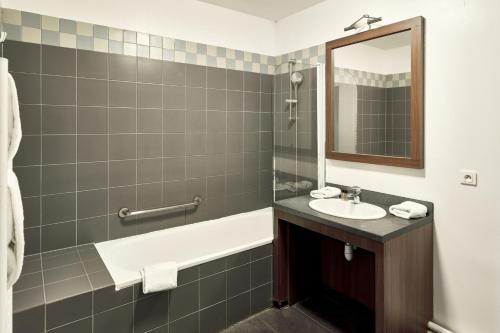 y baño con lavabo y bañera. en Zenitude Hôtel Résidences Roissy Village en Roissy-en-France