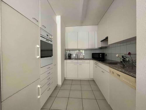 una cocina blanca con armarios y electrodomésticos blancos en Perfect combination of city and nature, en Pratteln