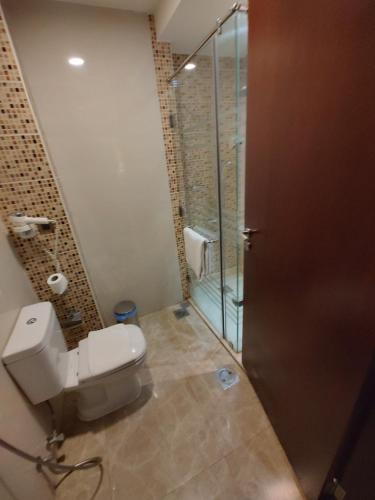 a bathroom with a toilet and a glass shower at فندق كارم العليا in Al Khobar