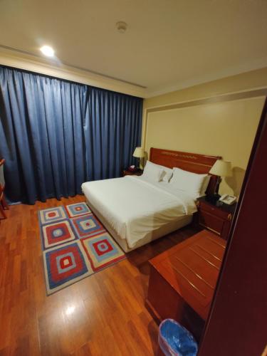a bedroom with a white bed and a large window at فندق كارم العليا in Al Khobar