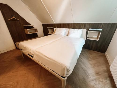 a bedroom with a large bed with white sheets and pillows at Hotel de Zeeuwse Stromen - Duinpark in Renesse