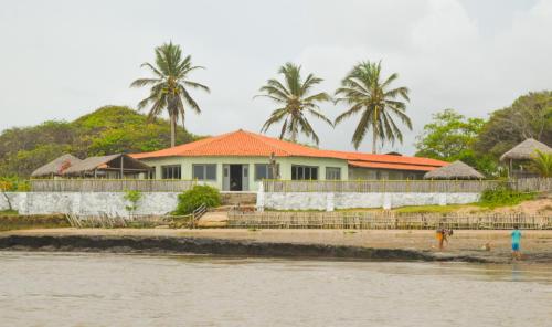 ein Haus mit einem orangenen Dach neben dem Wasser in der Unterkunft Paraíso das Canárias in Araioses