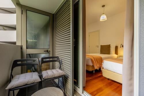 une chambre avec deux chaises et une chambre avec un lit dans l'établissement Kaizen Home & Pool, à Funchal