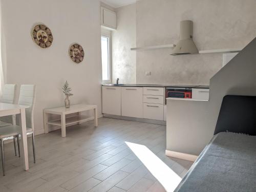 a kitchen with white cabinets and a table and a dining room at Bardolino Center Apartments in Bardolino