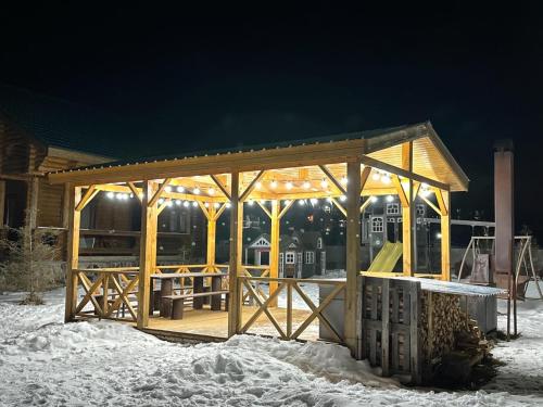 un gazebo in legno nella neve di notte di LOG HOUSE a Bakuriani