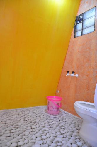 a bathroom with a toilet and a pink bucket at Dollies Mountain View in Kodaikānāl