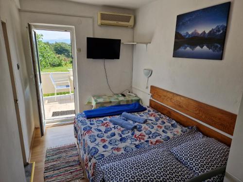 a bedroom with a bed with a television and a window at Apartments Nikol in Lopar