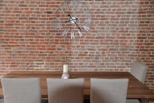 a table with chairs and a clock on a brick wall at Appartbrussels in Brussels
