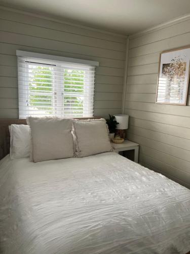 a bedroom with a bed with white sheets and two windows at Antique Retreat in Bathurst