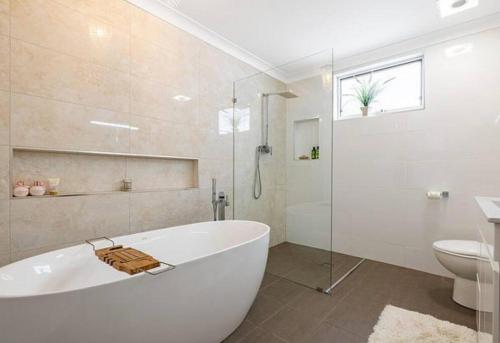 a white bathroom with a tub and a toilet at Antique Retreat in Bathurst