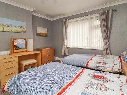 a bedroom with two beds and a desk and a window at 19 Slinger Road in Cleveleys
