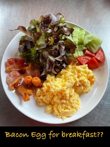 un plato de desayuno con huevos de tocino y verduras en Jing Jo Boutique Bungalow, en Sam Roi Yot