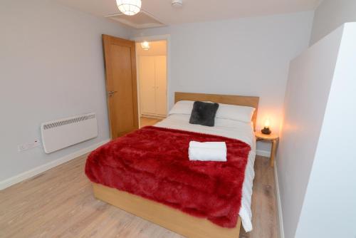 a bedroom with a large bed with a red blanket at The RED KEEP Fab Location - Two Bed - Two Bathrooms -Townhouse in Galway