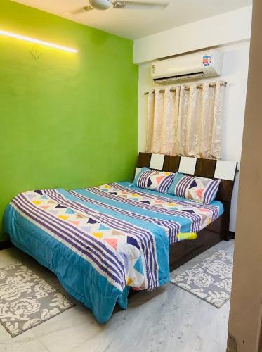 - une chambre avec des murs verts et un lit dans l'établissement Aashiyana, à Nashik