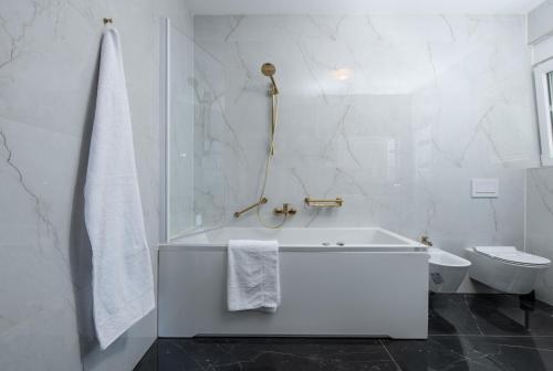 ein weißes Bad mit einer Badewanne und einem WC in der Unterkunft Luxury apartments Brijuni in Valbandon