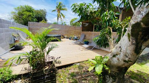 a wooden deck with two chairs on top of it at L'oasis tropicale in Bras-Panon