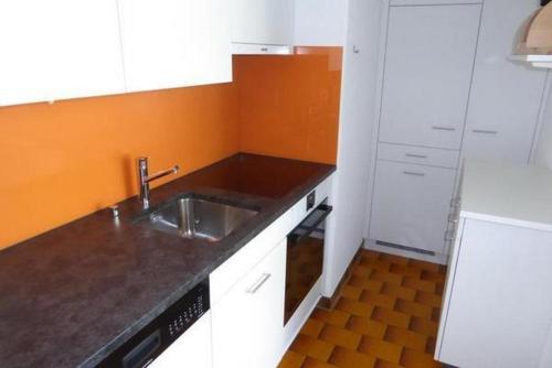 uma cozinha com um lavatório e uma parede laranja em Chesa Margretta, 2 ZWG im 1 Obergeschoss em Sils Maria