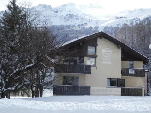 a house in the snow with mountains in the background at Chesa Margretta, Studio im 1 Obergeschoss in Sils Maria