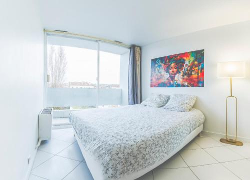 une chambre blanche avec un lit et une grande fenêtre dans l'établissement 2 Pièces très agréable proche de Paris et Disneyland, à Villemomble