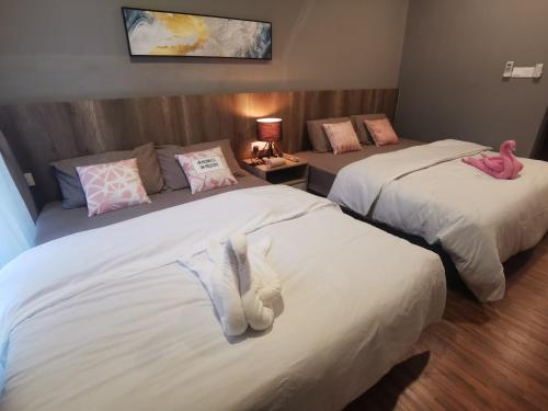 two beds in a hotel room with pink and white pillows at K AVENUE B17 house room near airport by Gc in Kota Kinabalu
