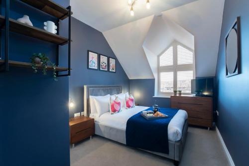 a bedroom with a bed with blue walls and a window at Elliot Oliver - Loft Style 2 Bedroom Apartment With Parking In The Docks in Gloucester