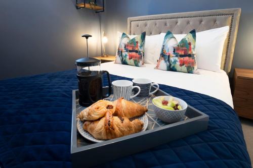 a tray with bread and fruit on a bed at Elliot Oliver - Loft Style 2 Bedroom Apartment With Parking In The Docks in Gloucester