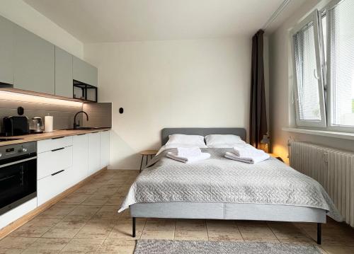 a white bedroom with a bed and a kitchen at New cozy studio, private parking in Bratislava