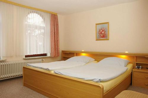 a bedroom with a large bed with white sheets at Ferienhof Jens Ferienwohnung 4 in Kronsgaard